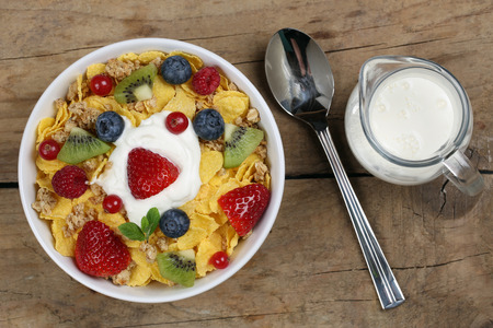 Fruit cereals with yogurt and milk, strawberries, raspberries, kiwi and blueberries from above