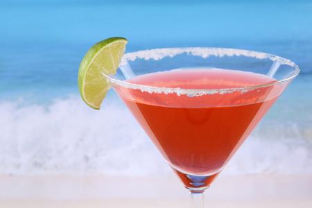 Red Martini cocktail with a lime on the beach while on vacationの写真素材
