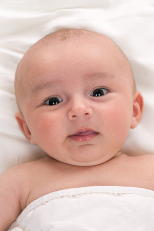 Portrait of a happy baby lying in bedの写真素材