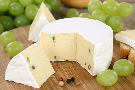 Cheese plate with soft cheese like Camembert or Brie on a wooden boardの写真素材