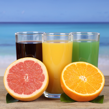 Juice from oranges, kiwi and grapefruit on the beachの写真素材