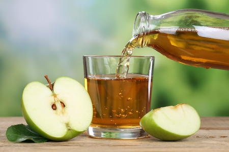 Apple juice pouring from green apples fruits in summer into a glassの写真素材