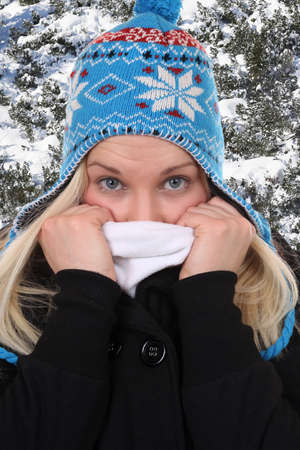 Young woman with a cap freezing in winter in the woodsの写真素材