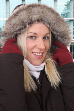 Smiling woman freezing in the cold in winter with warm clothing and gloves outdoor in townの写真素材