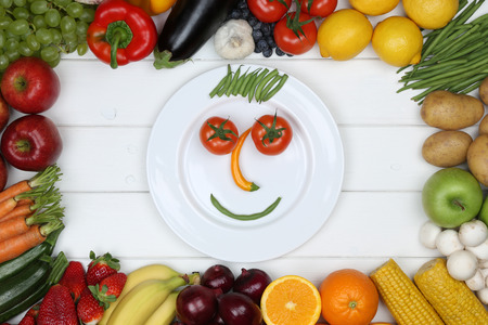 Healthy vegetarian and vegan eating smiling face from vegetables and fruits on plateの写真素材