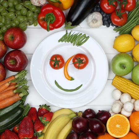 Vegetarian and vegan eating smiling face from vegetables and fruits on plateの写真素材