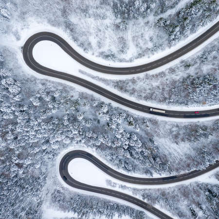 Winter snow winding road Serpentine Switchbacks forest woods season aerial photo view square droneの写真素材