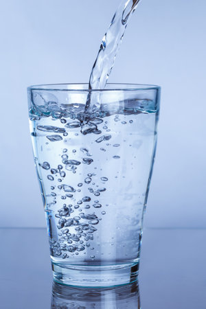 Pouring drink mineral water into a glass portrait format pourの写真素材