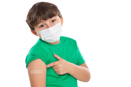 Child kid pointing on plaster after virus vaccination wearing face mask against Virus isolated on a white backgroundの写真素材