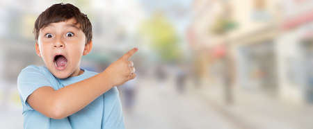 Child kid amazed surprised little boy pointing on ad advertising in town with copyspace copy space cityの写真素材