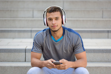 Listening to music young latin man with headphones listen smartphone smart phone outdoorの写真素材