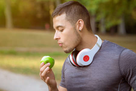 Young man eating an apple runner sports training workout fitness copyspace copy space outdoorの写真素材