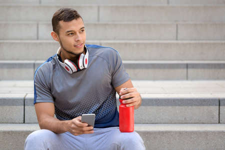 Young man listening to music listen headphones looking to the side copyspace copy space outdoorの写真素材