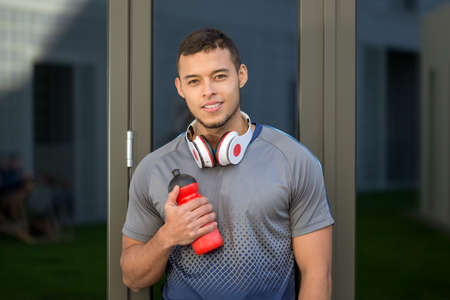 Smiling young latin man water bottle runner outdoor sports fitness training outsideの写真素材