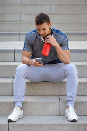 Young man looking at phone portrait format outdoorの写真素材
