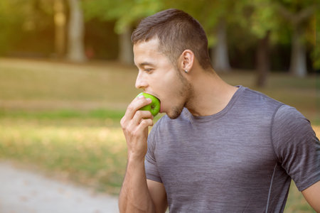 Young man eating apple in a park copyspace copy space runner sports training outdoorの写真素材
