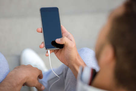 Young man looking at smartphone smart cell phone using cellphone copyspace copy space outdoorの写真素材