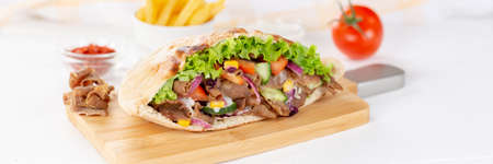 DÃ¶ner Kebab Doner Kebab slice fast food in flatbread with French Fries on a wooden board panorama slicedの写真素材