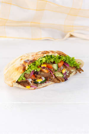 Doner Kebab Doner Kebab slice fast food in flatbread on a wooden board portrait format slicedの写真素材