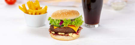 Hamburger Cheeseburger meal fast food with cola drink and French Fries on a wooden board panorama menuの写真素材