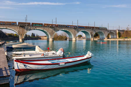 Peschiera del Garda, Italy - March 25, 2022: Freight cargo train on a bridge over Mincio river in Peschiera del Garda, Italy.のeditorial素材