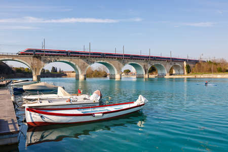 Peschiera del Garda, Italy - March 25, 2022: Frecciargento FS ETR 700 high-speed train of Trenitalia on a bridge over Mincio river in Peschiera del Garda in Italy.のeditorial素材