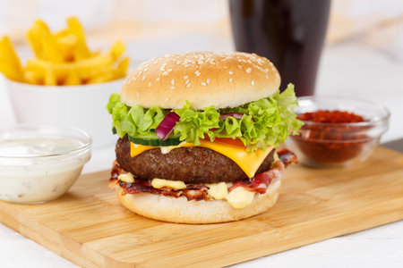 Hamburger Cheeseburger meal fast food with cola drink and French Fries on a wooden board menuの写真素材
