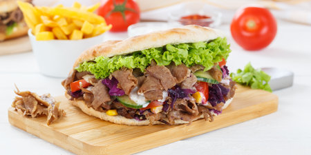 Doner Kebab Doner Kebap fast food meal in flatbread with French fries on a kitchen board panoramaの写真素材