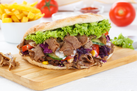Doner Kebab Doner Kebap fast food meal in flatbread with French fries on a kitchen boardの写真素材