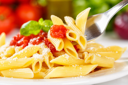 Penne Rigatoni Rigate eating pasta eat on fork meal from Italy lunch with tomato sauce on a plateの写真素材
