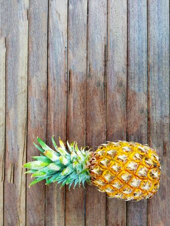 Single ripe juicy whole pineapple fruit on brown wooden table. の写真素材
