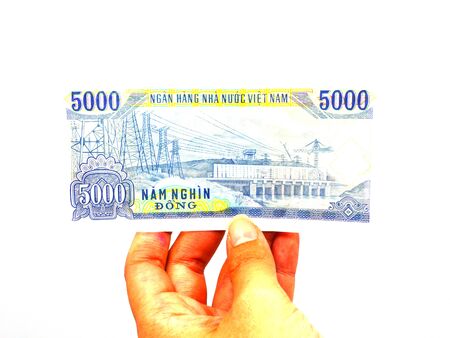 Holding Vietnamese currency 5,000 dong banknote by hand isolated on white backgroundの写真素材