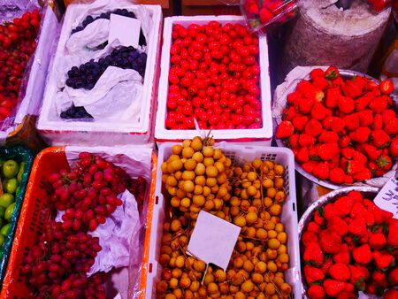 Basket on full of different several fruits such as grape, strawberry, longan and tomato の写真素材
