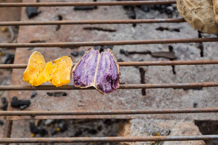 Grilled sweet potato on charcoal grill.の写真素材