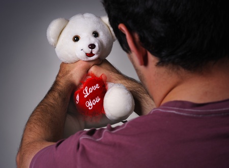 Frustrated man strangling a valentine teddy bearの写真素材