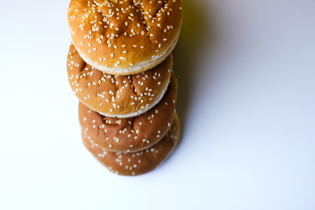 Closeup of tasty burger buns with sesame on a white and yellow backgroundの写真素材