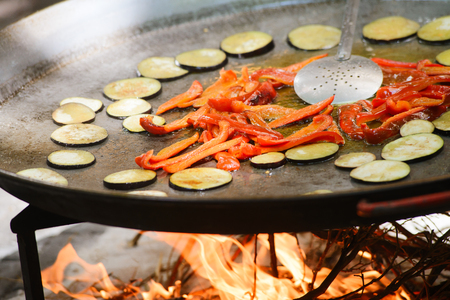 Prosess of cooking traditional spanish dish paella with cabbage, pepper, prawns and mussels on fireの写真素材