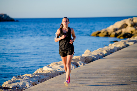 Young fit girl is running alone at beautiful sunset near the sea. Summer sport, freedom concept and...