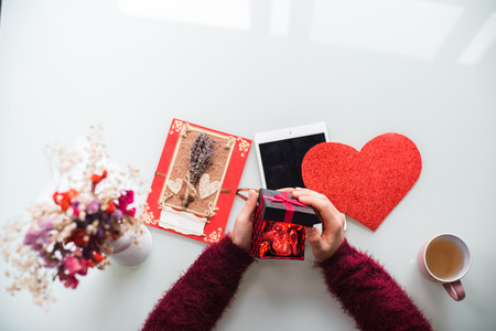 Close-up of the female hands opening a present on white background. Flowers, cup, card and heart on table. Valentine's Day, Love, Birthday, Holidays concept. Isolatedの写真素材