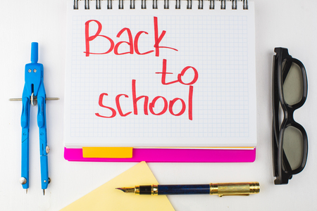 School supplies on a table with written words back to school in a notebookの写真素材