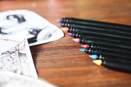 Close-up of tattoo equipment details on a wooden background. Colorful inks, sketches and brushes.の写真素材