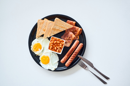 Traditional full English breakfast with fried eggs, sausages, beans, bacon and toasts isolated on white background. Top view.の写真素材