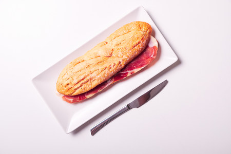 Tasty sandwich made of crispy baguette and ham iberico isolated on white backgroud. Spanish bocadillo.の写真素材