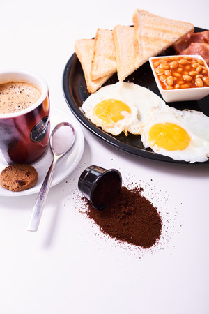 Close-up of traditional full English breakfast with fried eggs, sausages, beans, bacon, toasts and orange juice isolated on white background.の写真素材