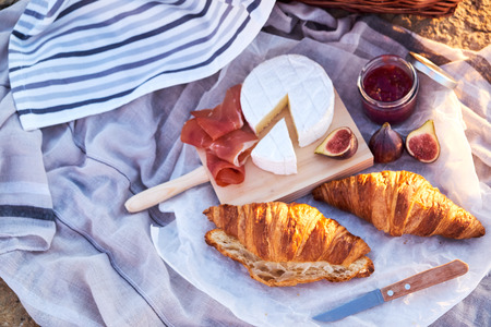 Top view of beautiful romantic picnic composition with croissants, bread, jam, cheese, figs and jamon.の写真素材
