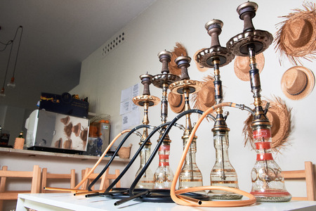 Group of eastern hookahs with black pipes on table in cafe. Shisha smoking concept.