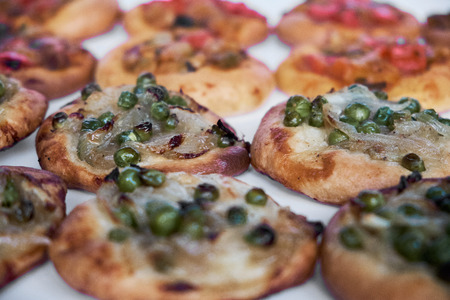 Close-up of freshly baked mini pizzas cocas on white background. Traditional Spanish pastry with vegetables.の写真素材