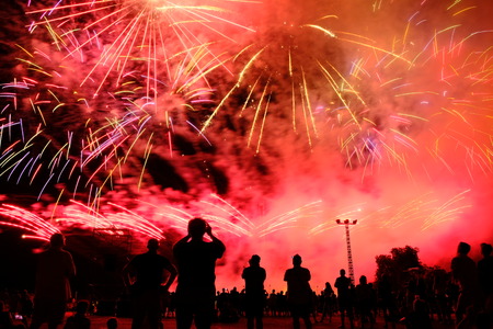 Long exposure image of people silhouettes watching pyrotechnic show and recording video with smartphones at night. Celebration ceremony.の写真素材