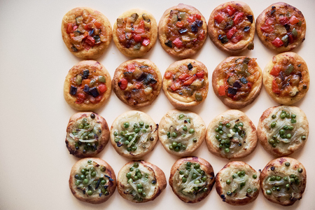 Many freshly baked mini pizzas Cocas on white background. Traditional Spanish pastry with vegetables. Copy space. Top view.の写真素材