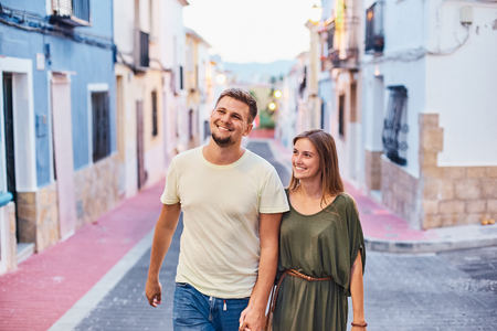 Happy young couple in love walking along the small street and holding hands.